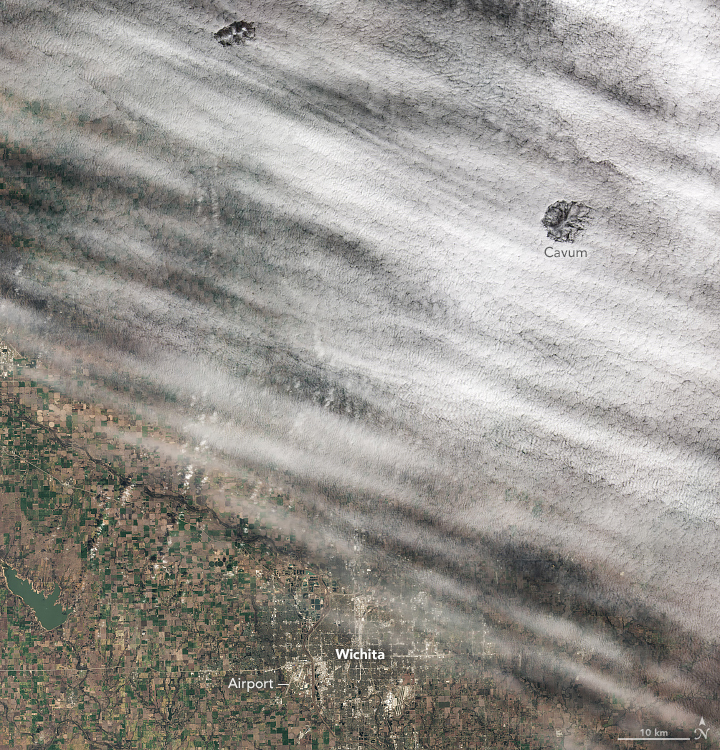 A satellite image looking down on Wichita shows lumpy linear clouds covering half of the city. Two circular gaps in the clouds (cavum) are visible in the upper part of the image.