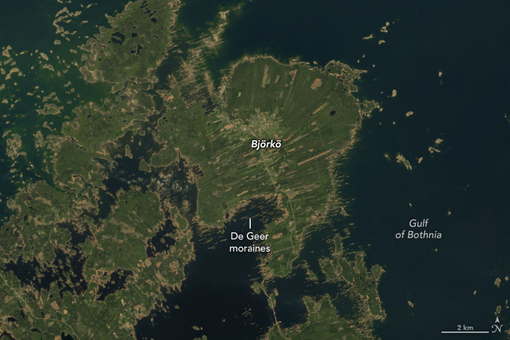 A⁣ detailed satellite image of the island of ⁢Björkö in Finland's Kvarken Archipelago. The​ island appears to be divided into elongated fields colored tan and different