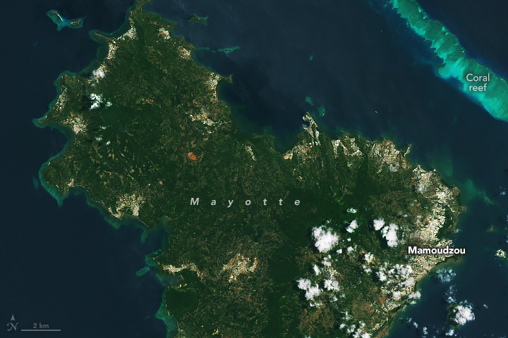 A satellite image of the main island of Mayotte (referred to as Grande Terre) taken in October 2024. The volcanic island showcases a rugged coastline and dark green foliage inland.