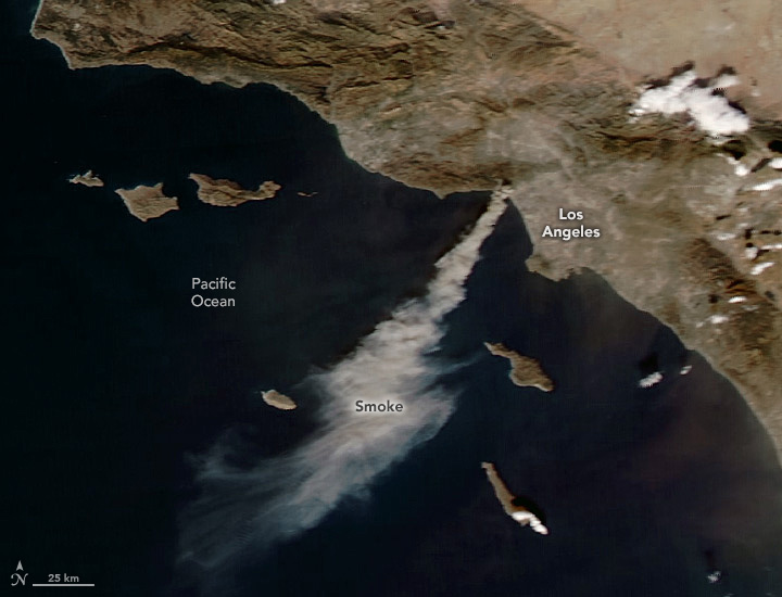 A satellite image shows smoke streaming from an area north of Los Angeles, out into the Pacific Ocean.