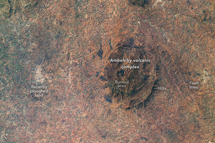 A satellite image of brown, semi-concentric hills in Madagascar. Most of the landscape in the image is light brown, with some greener forested areas along the left third of the image.